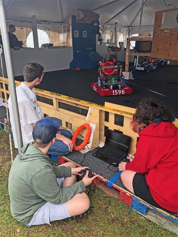 Mentor and students with computer working on code for the robot.