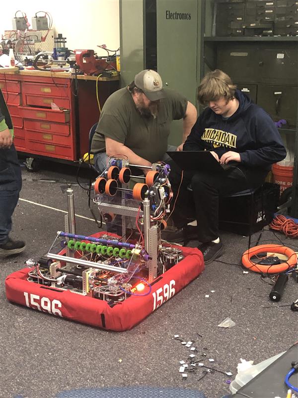 Mentor and student looking at robot.