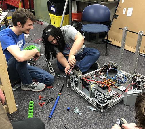 Two students working on the robot's drive wheels.